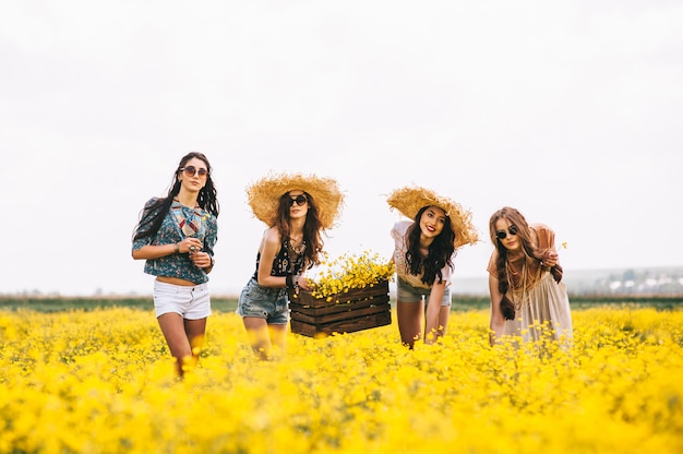 quatre belle fille hippie dans un champ de fleurs jaunes