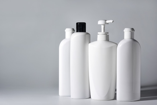 Quatre bouteilles en plastique blanc avec des shampooings et des revitalisants capillaires sur fond blanc.