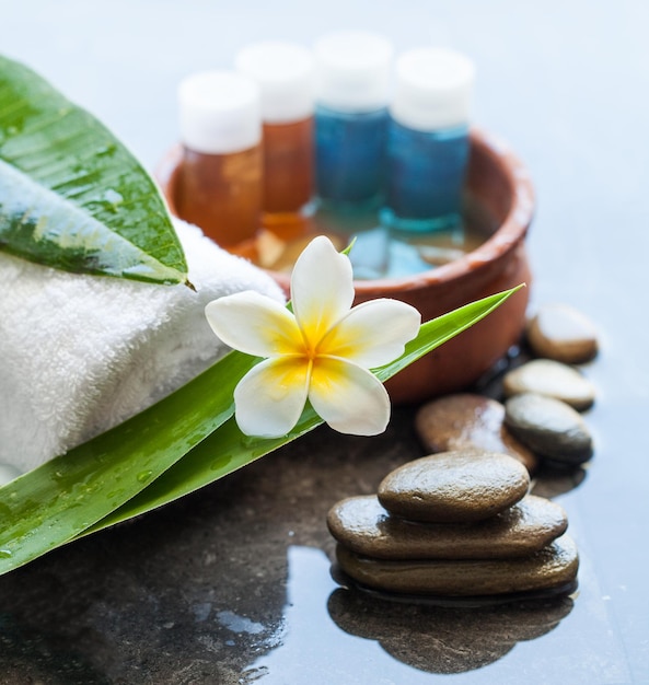 Quatre bouteilles de Spa ou de bien-être avec un bol de fleurs tropicales de serviette d'eau