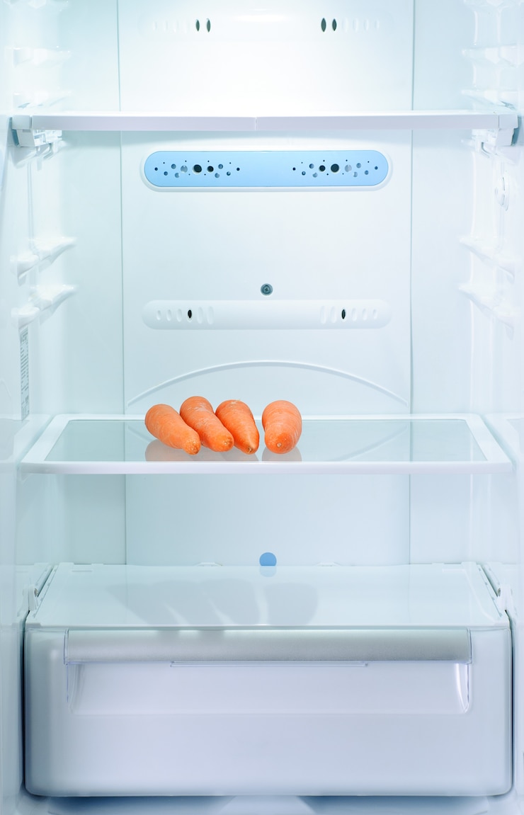Photo quatre carottes fraîches et crues au réfrigérateur