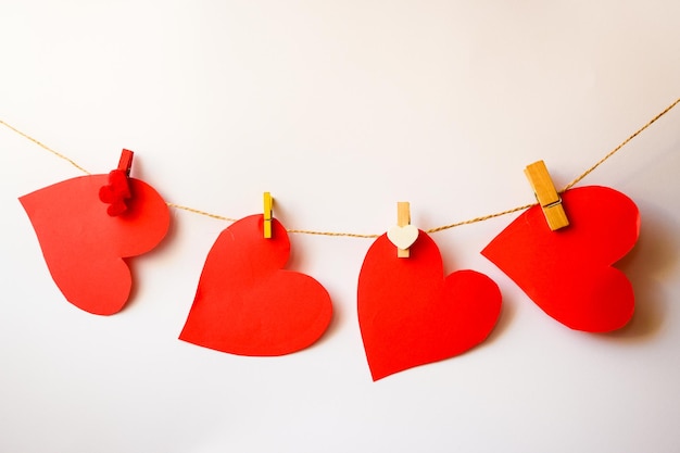 Quatre coeurs rouges accrochés à une corde avec des mini pinces à linge