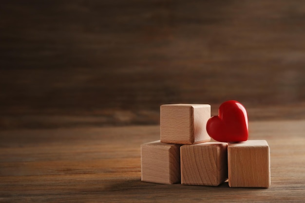 Quatre cubes en bois avec coeur rouge sur fond de bois je t'aime inscription