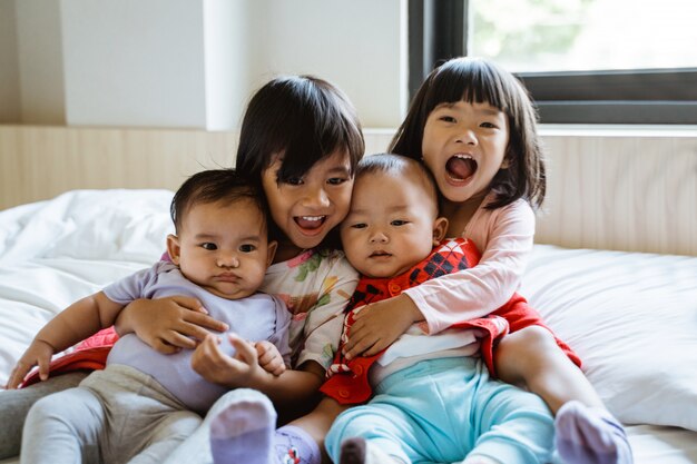 Quatre enfants asiatiques rient assis sur le lit