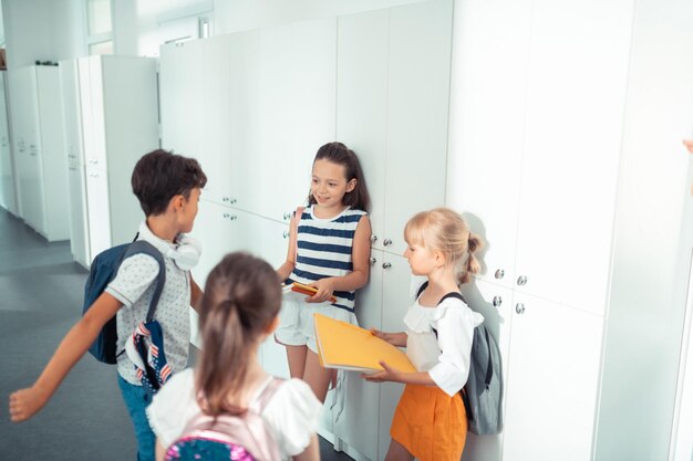 Quatre enfants debout près des casiers et discutant de la journée scolaire