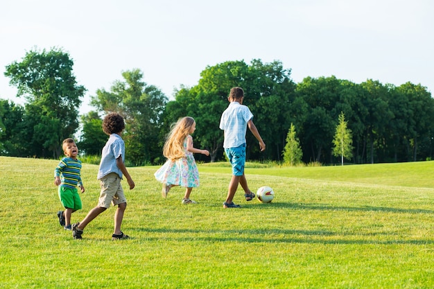 Quatre enfants jouent sur la clairière du soir.