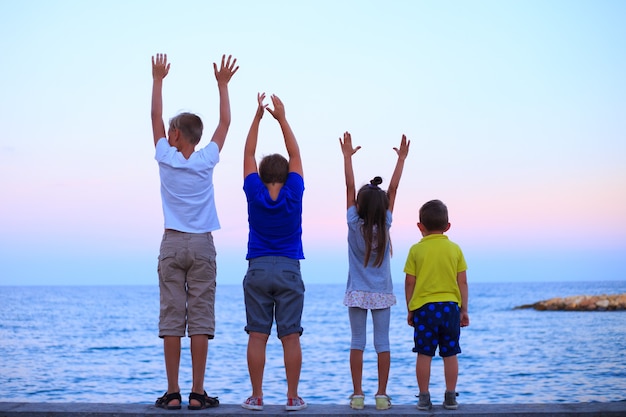 Quatre enfants sur la vocation de plage Jeune famille en vacances s'amusent beaucoup