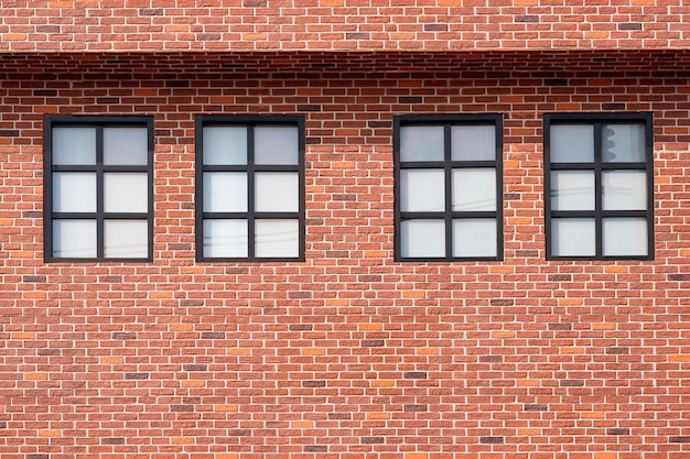 Quatre fenêtres en verre dépoli sur le mur de briques de 2 étages de maison de style vintage