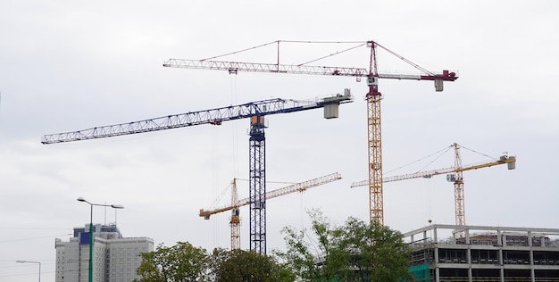 Quatre grues de construction dans le ciel gris