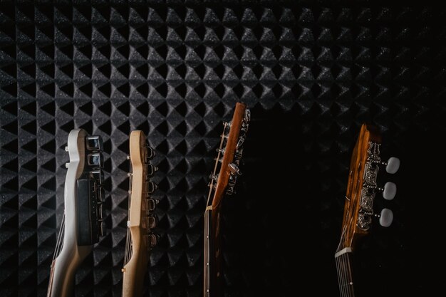 Photo quatre guitares guitare acoustique et guitare électrique sur un fond noir dans un studio de musique musiciens papier peint la musique nous réunit