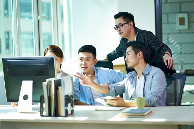 quatre jeunes entrepreneurs asiatiques discutant d'affaires au bureau