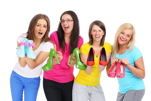 Quatre jeunes femmes tenant des chaussures de couleur sur fond blanc