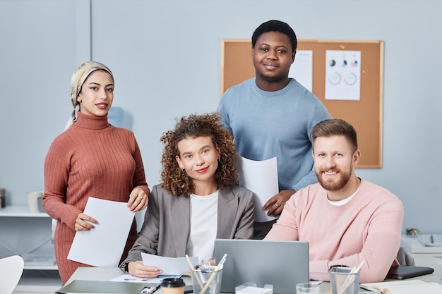 Photo quatre jeunes managers interculturels heureux en tenue décontractée regardant la caméra