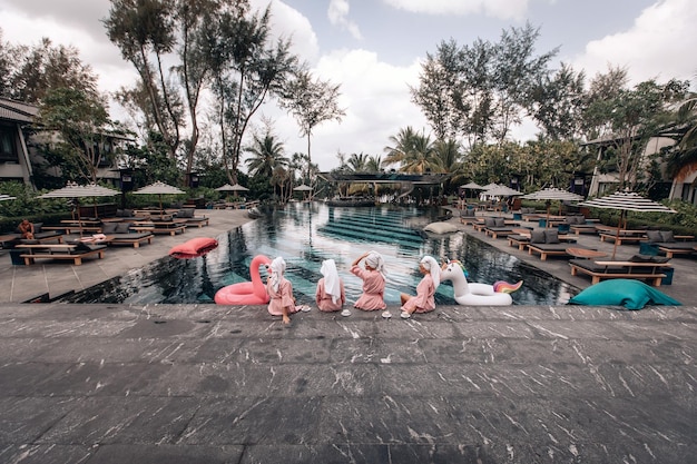 Quatre Joyeux Amis S'amusent Au Bord De La Piscine à Côté De L'hôtel. Quatre Femmes Adultes Minces Et En Forme Portant Les Mêmes Vêtements Posent. Vue Arrière