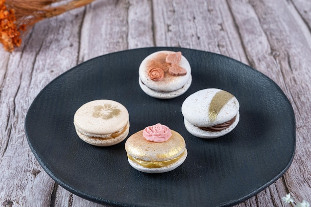 Quatre macarons décorés d'encre comestible et de fondant sur une plaque noire