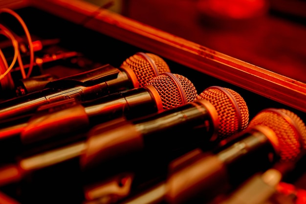 Quatre microphones de secours de rechange sur les coulisses en rétroéclairage rouge coloré derrière la scène. photo de haute qualité