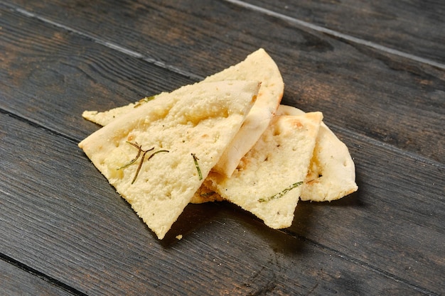 Quatre morceaux de focaccia aux herbes sur table en bois