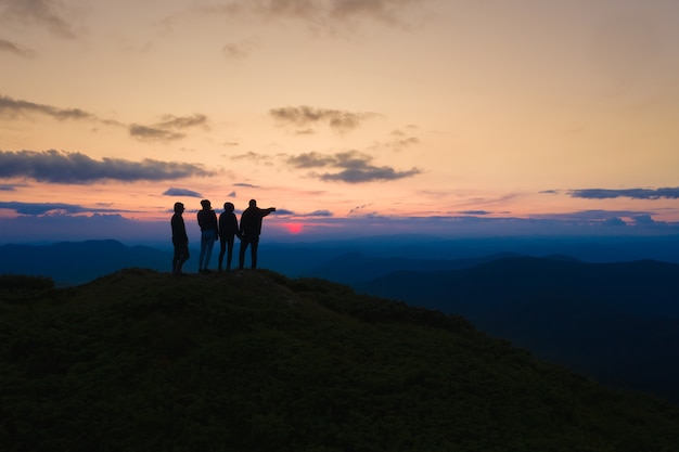 Les quatre personnes debout sur la belle montagne sur fond de lever de soleil