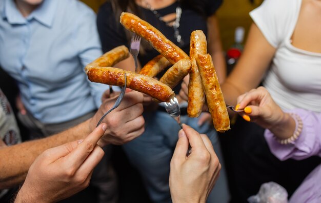 Quatre personnes tiennent un hot-dog ensemble.