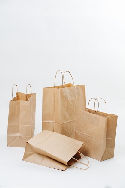 Quatre sacs en papier brun vides disposés dans une composition sur fond blanc. L'un est à plat sur le côté. Objets compostables écologiques.