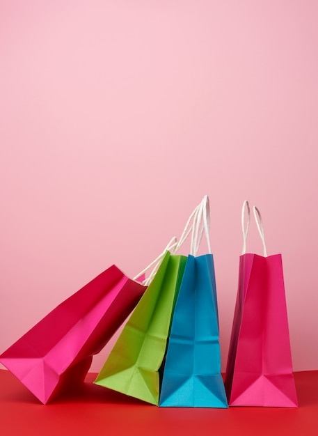 Quatre sacs en papier multicolores vides pour faire du shopping et des cadeaux avec des poignées blanches