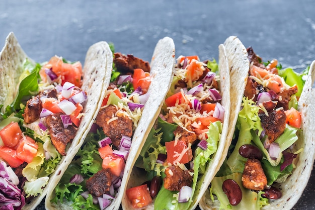 Quatre tacos mexicains sur une surface noire