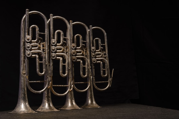 Photo quatre vieux instruments à vent en laiton se tiennent sur une table sur un fond noir