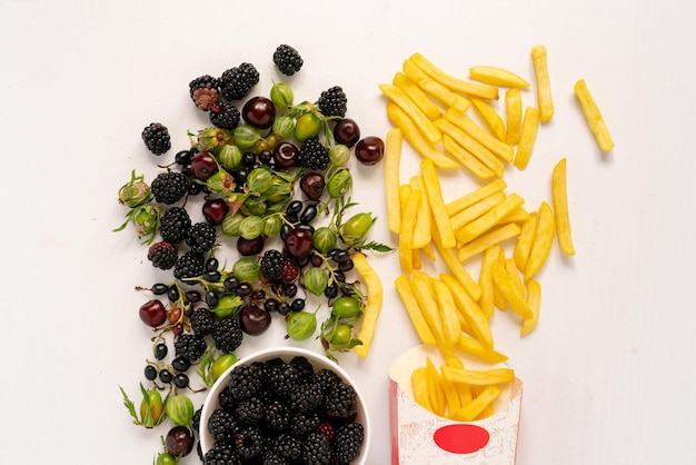 Que choisirez-vous Des baies fraîches et saines sortent du bol ou des frites de pommes de terre indésirables de la boîte en papier