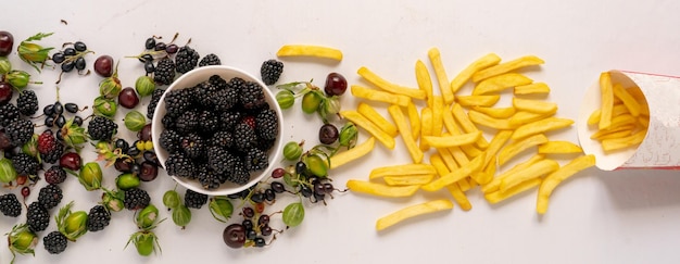 Que choisirez-vous Des baies fraîches et saines sortent du bol ou des frites de pommes de terre indésirables de la boîte en papier