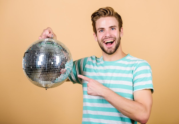 Que diriez-vous de faire la fête Un bel homme tient une boule disco Danse disco Boîte de nuit Musique rétro Un gars vous invite à la fête Mille petits miroirs reflétant des lumières créant une atmosphère disco Joyeux dj homme