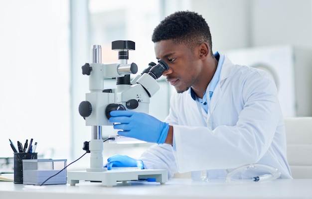 Quelle découverte intéressante Photo recadrée d'un jeune scientifique masculin concentré regardant des échantillons de test à travers un microscope à l'intérieur d'un laboratoire pendant la journée