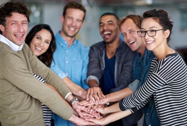 Quelle équipe Portrait d'un groupe heureux de collègues tenant leurs mains ensemble dans l'unité