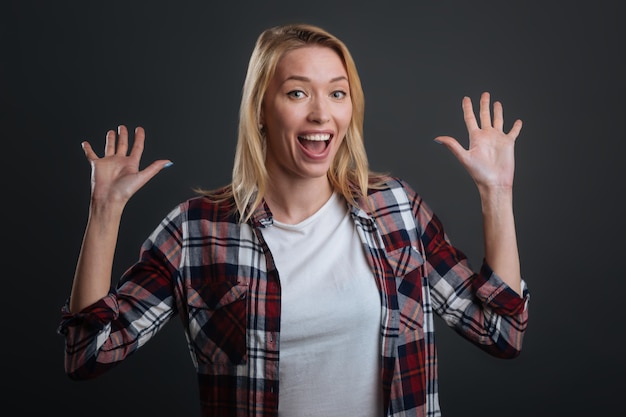 Quelle surprise. Magnifique jeune femme expressive jetant ses mains dans l'excitation tout en étant très émotionnelle et debout isolée sur fond gris