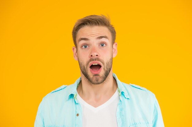 Quelle surprise le style de mode décontractée d'été masculin surpris mec a coiffé les cheveux sur fond jaune émotions humaines garçon sexy avec une coiffure à la mode porter une chemise bel homme mal rasé avec des poils