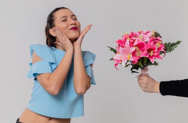 Quelqu'un donne un bouquet de fleurs à une jolie jeune femme ravie