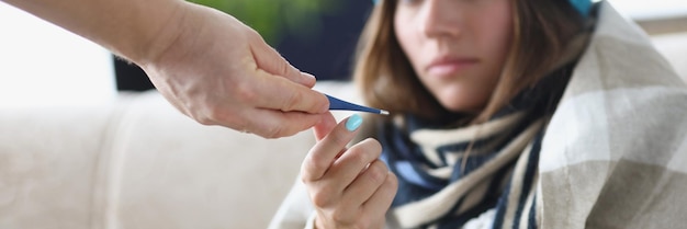 Quelqu'un donne un thermomètre à une jeune femme pour mesurer la température