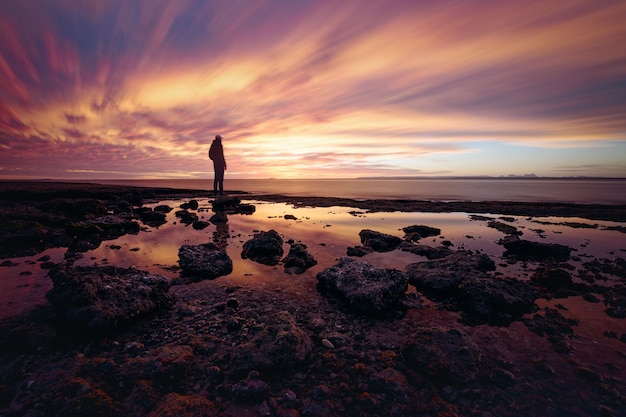 Photo quelqu'un profitant du coucher de soleil sur la côte rocheuse à la lagune de san ignacio, baja california, mexique