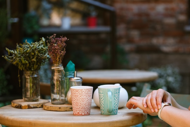 Quelqu'un se fait tard. Femme vérifiant l'heure sur sa montre en attendant qu'il prenne une tasse de café