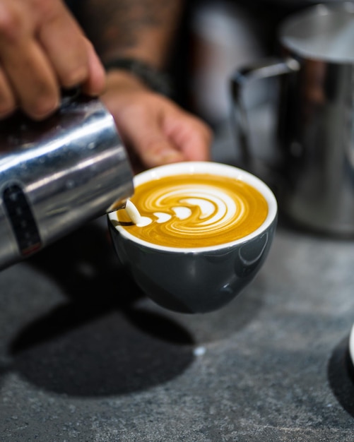 Quelqu'un versant un café dans une tasse sur la table.