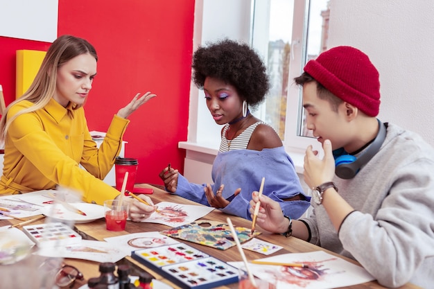 Quelques arguments. Trois étudiants en art créatifs et élégants ayant des arguments tout en travaillant ensemble