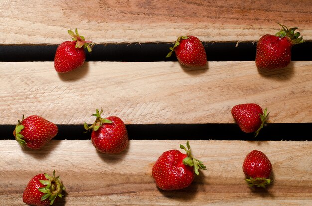 Quelques baies mûres de fraises sur des plaques de bois, vue de dessus