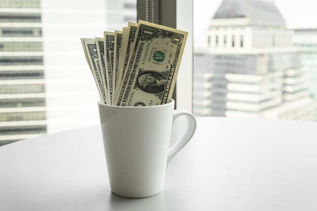 Quelques billets d'un dollar avec une tasse de café sur la table pour économiser de l'argent concept/selective focus