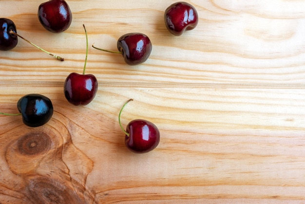 Quelques cerises mûres sur un fond de bois naturel à plat tourné avec espace de copie