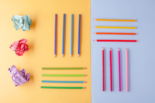 Quelques crayons de couleur et du papier froissé de couleur sur fond jaune bleu Développer la créativité