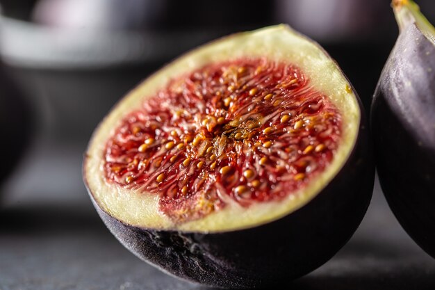 Quelques figues dans un bol noir sur une table en béton foncé.