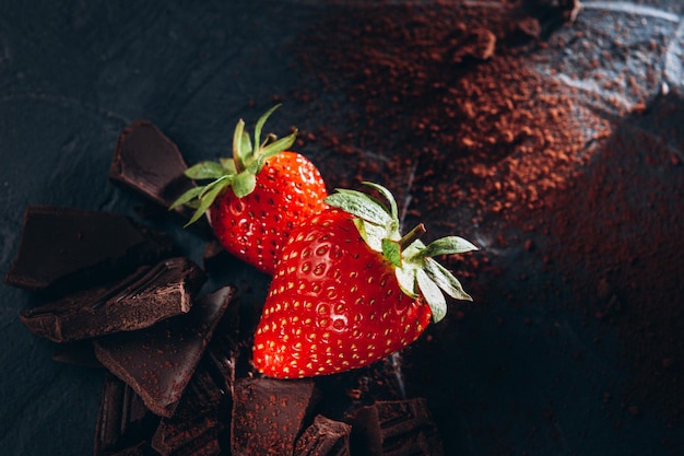 Quelques fraises au chocolat et cacao sur fond sombre