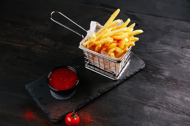 Quelques frites prêtes à être mangées et de la sauce dans un récipient