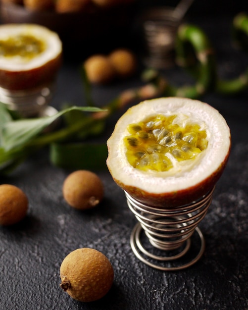 Quelques litchis, fruits de la passion et bambous sur fond sombre. Style asiatique