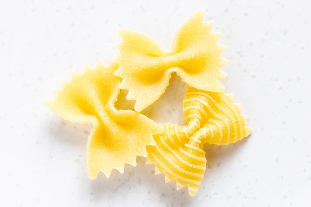 Quelques morceaux de pâtes farfalle non cuites sur gris