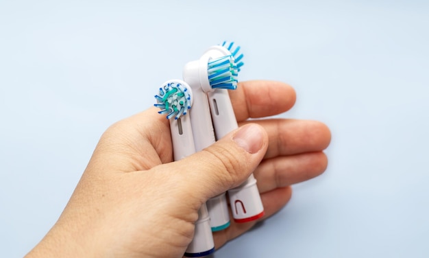 quelques pièces de réserve pour brosse à dents électrique dans des mains d'enfant ou de femme ou sur dos bleu ou orange clair