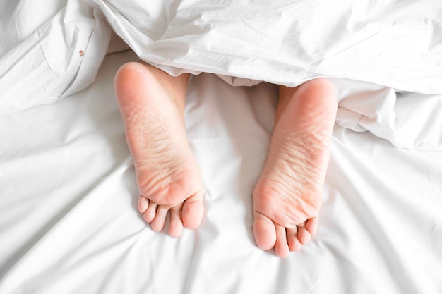 Quelques pieds sous les draps sur le lit à la maison